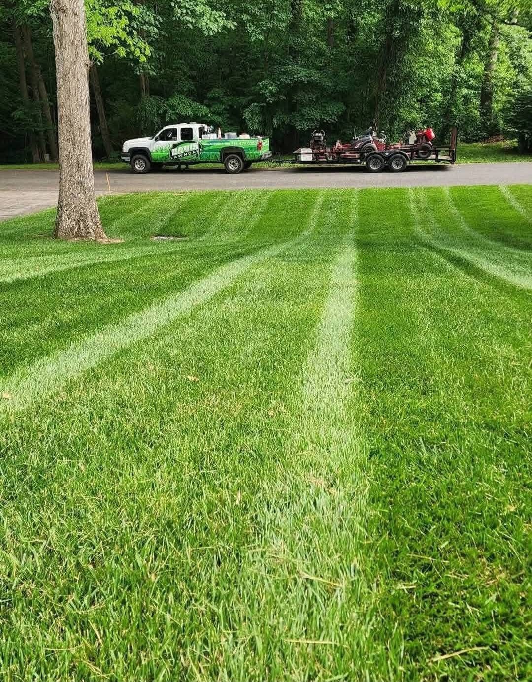 Davis Lawn Care branded truck and trailer with mowing equipment beside a freshly striped lawn